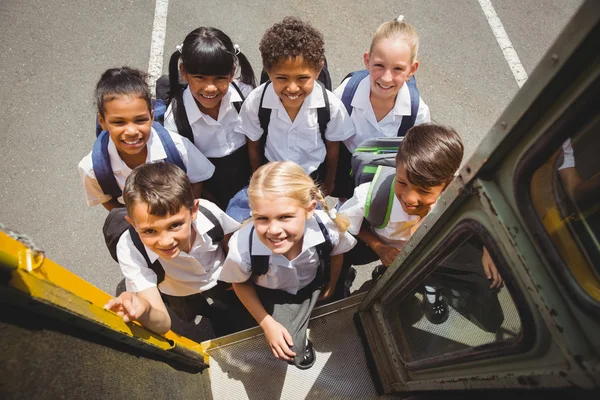 Bonito crianças em idade escolar entrar no ônibus escolar — Fotografia de Stock