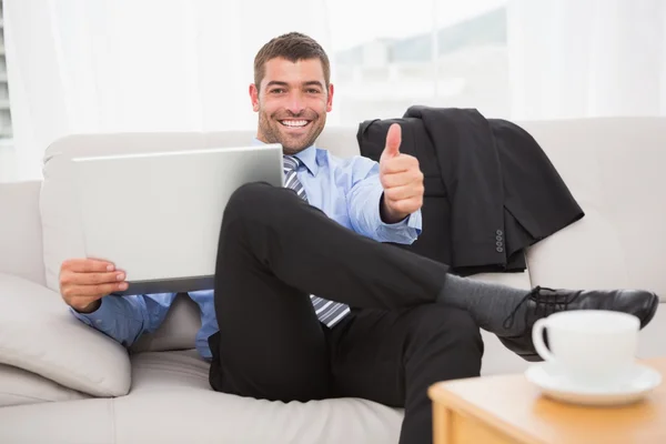 Relaxante empresário em um sofá com um laptop — Fotografia de Stock