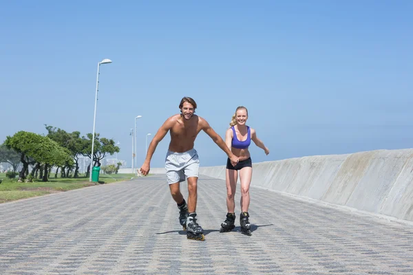 Fit couple rollerblading together on promenade — Stock Photo, Image