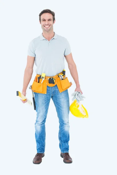 Repairman holding spirit level and hardhat — Stock Photo, Image