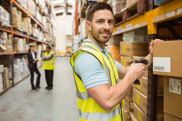 Warehouse worker scanning box while smiling at camera — Stock Photo, Image