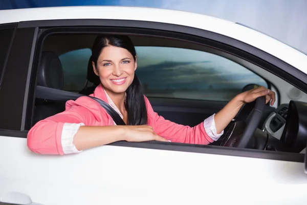 Smiling customer sitting at the wheel of a car for sale — Stock Photo, Image