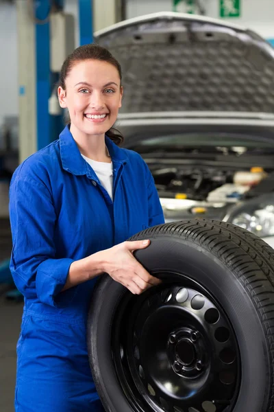 Mechanic smiling holding tire — Stock Photo, Image