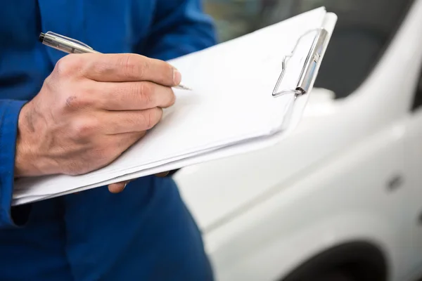 Mechanic writing on clipboard — Stock Photo, Image