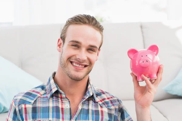 Sonriente hombre mostrando rosa alcancía — Foto de Stock