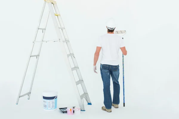 Hombre con rodillo de pintura de pie por escalera — Foto de Stock