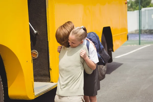 Mãe abraçando sua filha de ônibus escolar — Fotografia de Stock