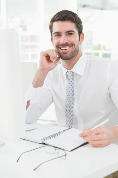 Smiling businessman writing on notepad — Stock Photo, Image