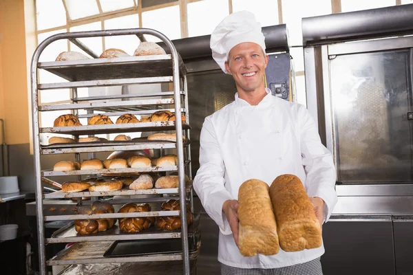 Smiling baker showing loaves of bread — Stock Photo, Image