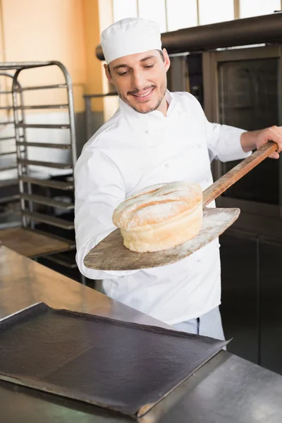 Happy baker taking out fresh loaf — Stock Photo, Image