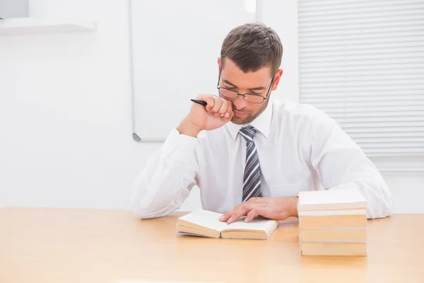 Geschäftsmann sitzt am Schreibtisch und liest Bücher — Stockfoto