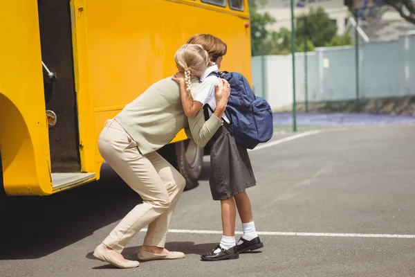 Mãe abraçando sua filha de ônibus escolar — Fotografia de Stock