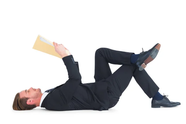 Relajado hombre de negocios mintiendo y leyendo documento — Foto de Stock