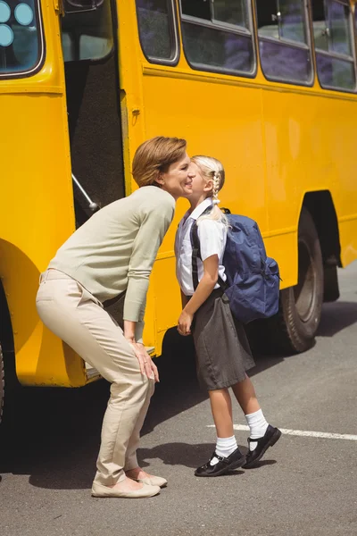 Мама целует свою дочь на школьном автобусе — стоковое фото