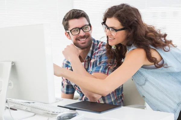 Lächelndes Team mit Computer am Schreibtisch — Stockfoto