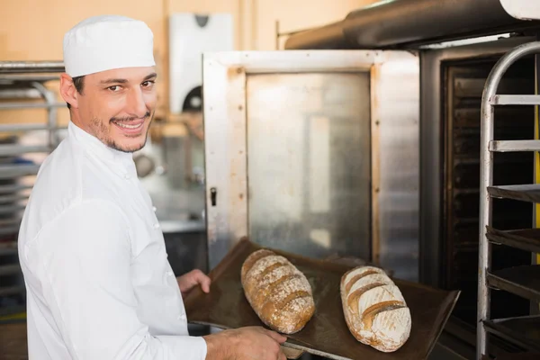 Happy baker holding tray of fresh bread — Stock Photo, Image