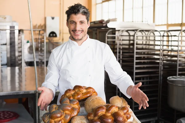 Smiling baker showing board of breads — Stock Photo, Image