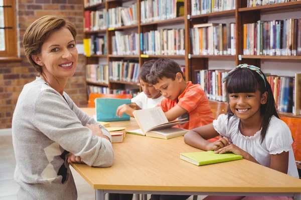 Ładny uczniowie i nauczyciel czytanie w bibliotece — Zdjęcie stockowe