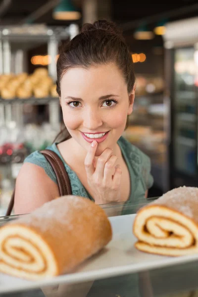 Pretty brunette looking at swiss roll — Stock Photo, Image