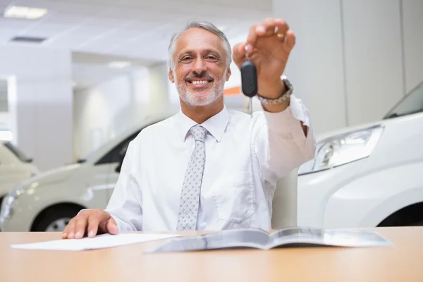 Vendeur souriant donnant des clés de voiture à un client — Photo