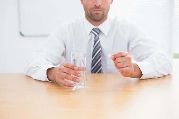 Seriös affärsman hålla glas vatten och tablett — Stockfoto