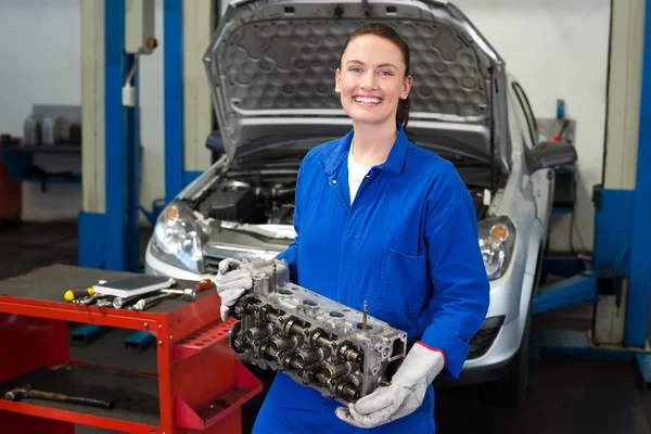 Mecânico segurando um motor e sorrindo — Fotografia de Stock