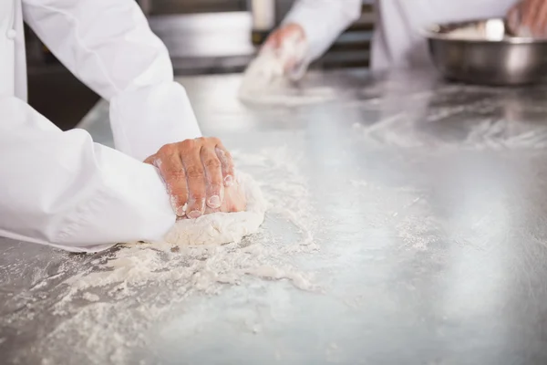 Bakkers kneden van deeg aan balie — Stockfoto