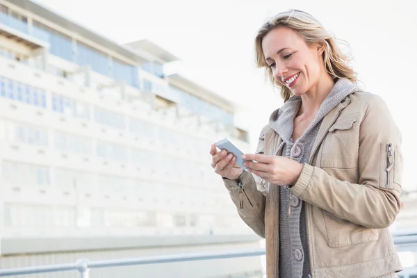 Usmíval se blondýna postavení a textových zpráv — Stock fotografie