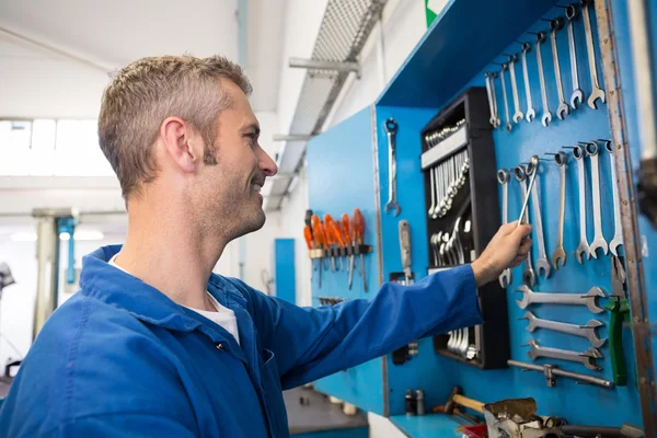 Mechanic taking a tool from wall — Stock Photo, Image
