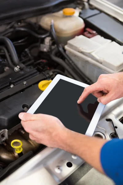 Mecánico usando la tableta para arreglar el coche — Foto de Stock