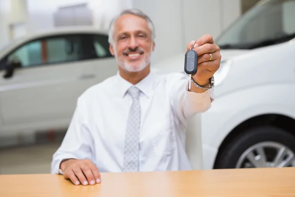 Vendedor sorridente que dá chaves de um carro do cliente — Fotografia de Stock