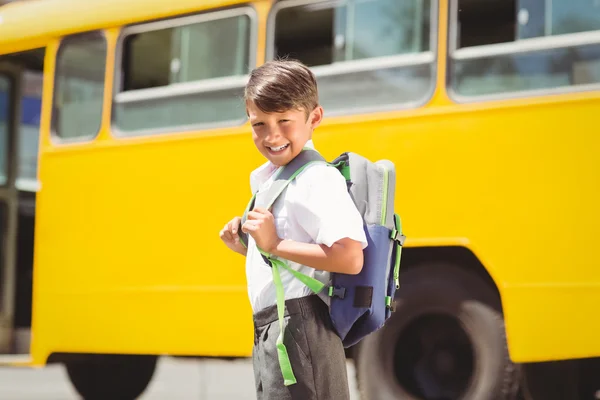 Симпатичный ученик идет к школьному автобусу — стоковое фото
