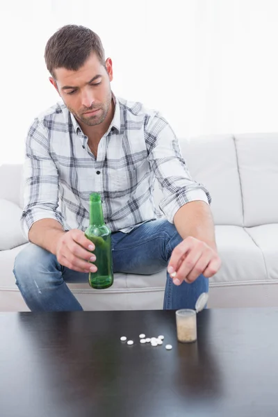 Preocupado hombre con una cerveza y su medicina puesta — Foto de Stock