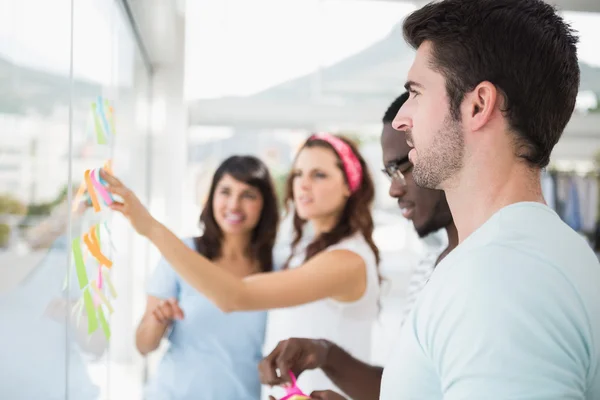 Smiling teamwork reading sticky notes — Stock Photo, Image