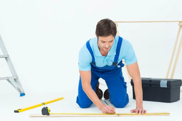Worker marking on wood while measuring — Stock Photo, Image