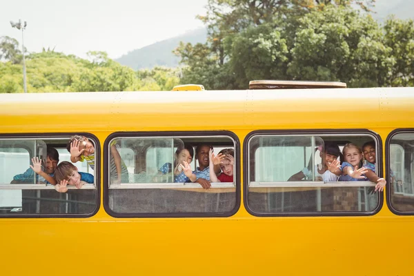 Söta elever ler mot kameran i skolbussen — Stockfoto