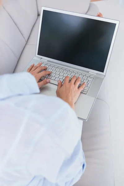 Kadın kanepede dizüstü bilgisayarda yazarak — Stok fotoğraf