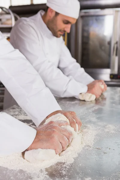 Bakers kneading dough at counter — Stock Photo, Image