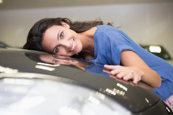 Lächelnde Frau umarmt ein schwarzes Auto — Stockfoto