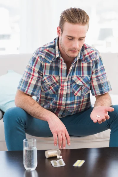 Resaca hombre con la medicina puesta en la mesa —  Fotos de Stock