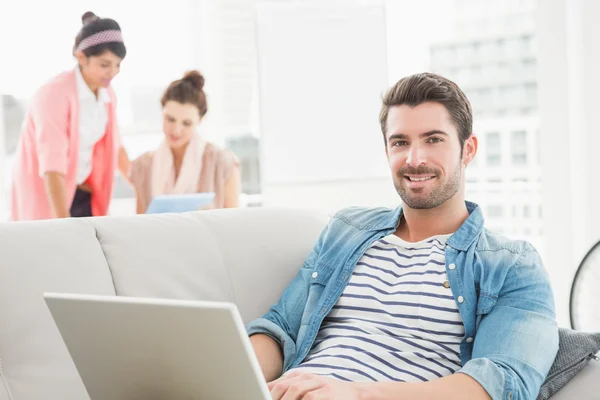 Cheerful businessman using laptop on sofa — Stock Photo, Image