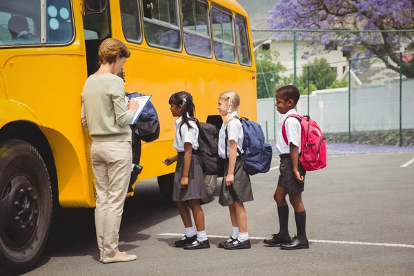 Bonito crianças em idade escolar esperando para entrar no ônibus escolar — Fotografia de Stock