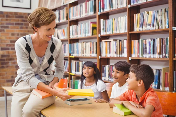 Schattig leerlingen en leraar op zoek naar boeken in bibliotheek — Stockfoto