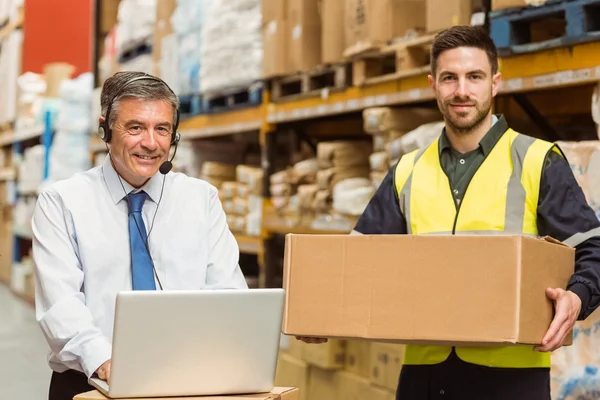 Smiling warehouse manager using laptop — Stock Photo, Image