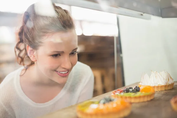 Pretty brunette looking at tarts — Stock Photo, Image