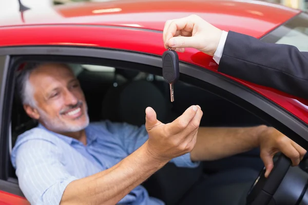 Homem dirigindo carro enquanto vendedor dando chave — Fotografia de Stock