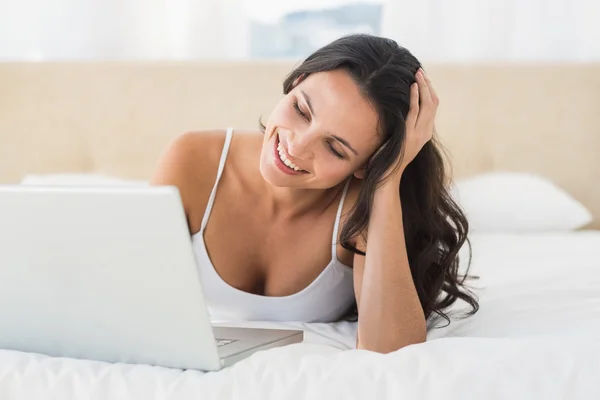 Happy brunette using her laptop — Stock Photo, Image