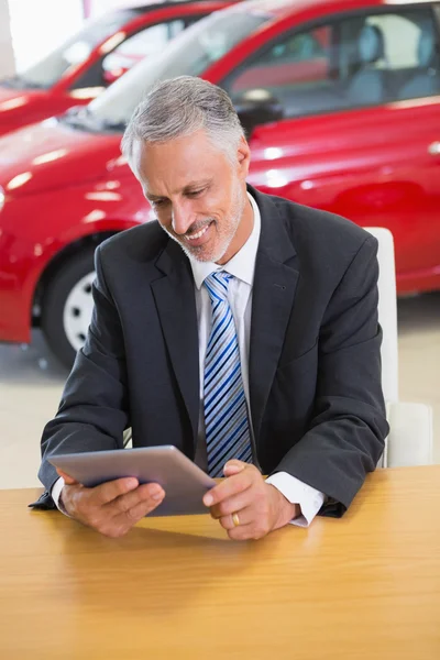 Hombre de negocios sonriente usando tableta en su escritorio — Foto de Stock