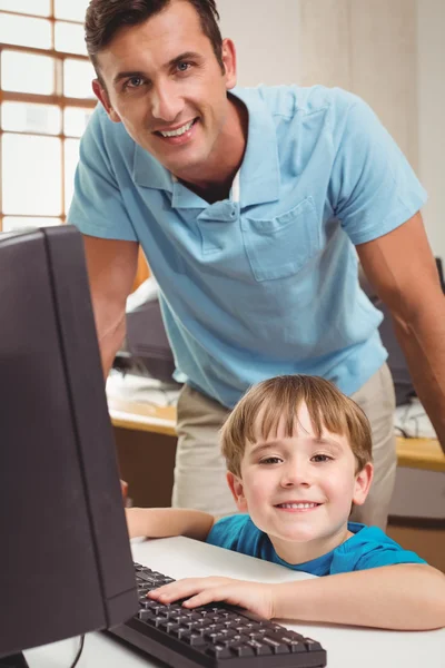 Cute pupil in computer class with teacher Royalty Free Stock Images