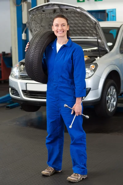 Mechanic smiling at holding tire Royalty Free Stock Images